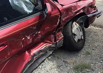 Red car with crumpled side and tire from a motor vehicle accident