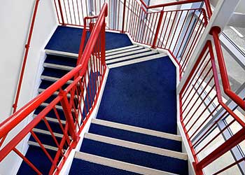 Staircase with red railing and blue carpeting