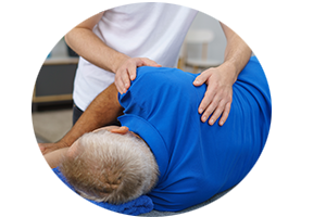 Man in a blue shirt lying on his side as a chiropractor works on his shoulder muscle